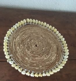 Dessous de plat en rotin et coquillages en bordure.