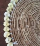 Dessous de plat en rotin et coquillages en bordure.