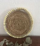 Dessous de plat en rotin et coquillages en bordure.