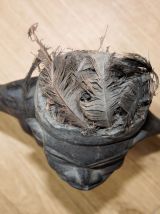 Statuette fétiche en bois avec plumes sur la tête et graines