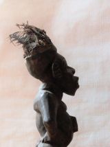 Statuette fétiche en bois avec plumes sur la tête et graines