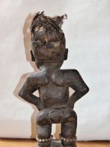 Statuette fétiche en bois avec plumes sur la tête et graines