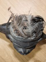 Statuette fétiche en bois avec plumes sur la tête et graines
