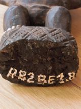 Statuette fétiche en bois avec plumes sur la tête et graines