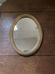 Miroir ovale au cadre en bois doré.