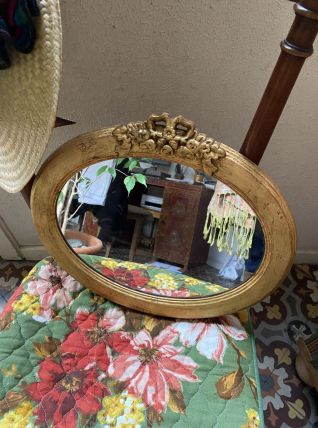 Miroir ovale avec noeud en bois doré.